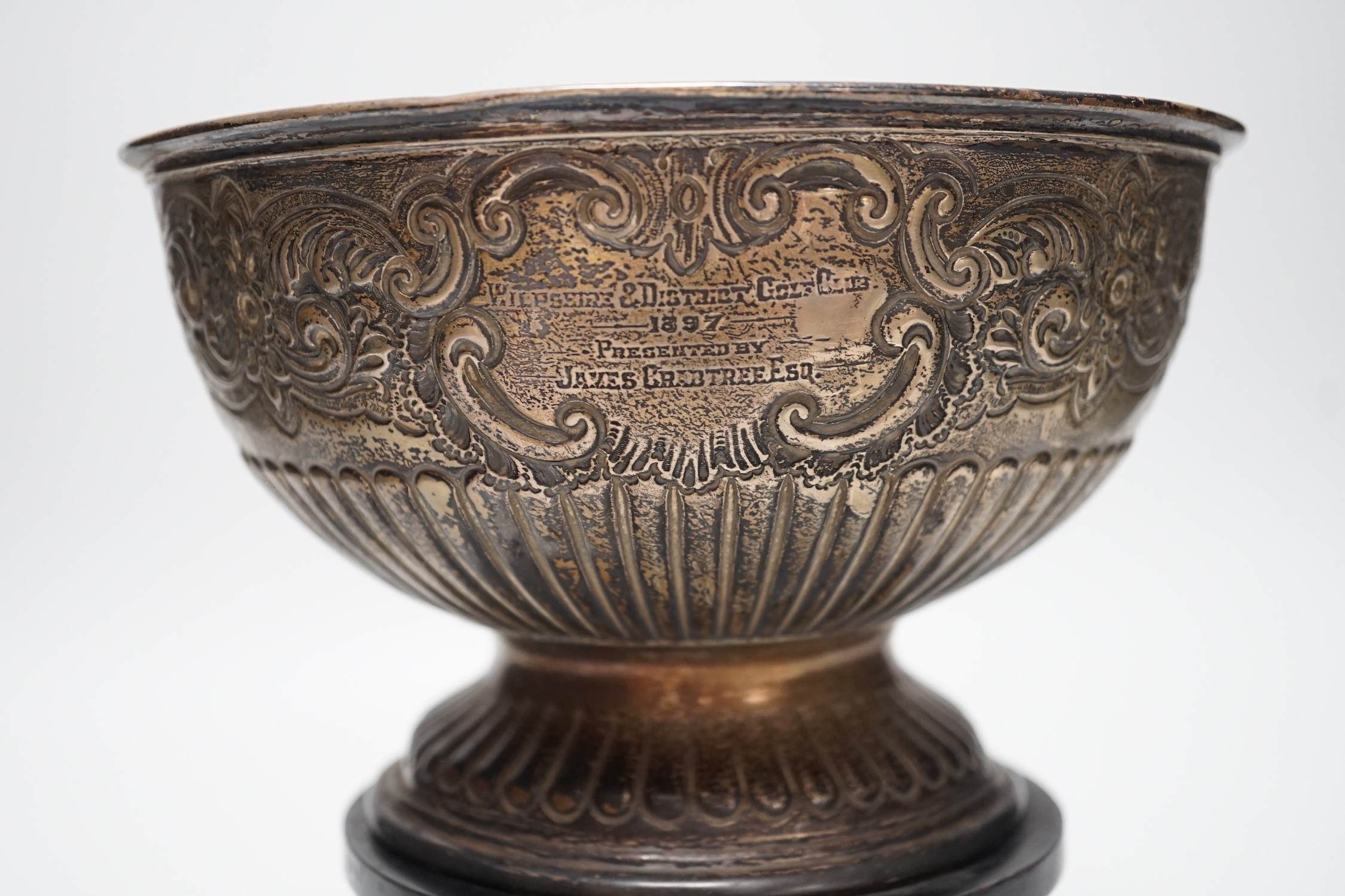 A late Victorian demi fluted and embossed silver presentation rose bowl, with engraved inscription, James Deakin & Sons, Sheffield, 1896, diameter 19.5cm, 12.2oz, on ebonised plinth